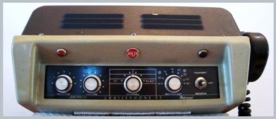 Modern looking transceiver with 4 knobs and a mirophone hanging on the right side.