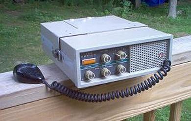 Tabletop Radio transceiver with 5 small knobs and speaker grill on right front.
