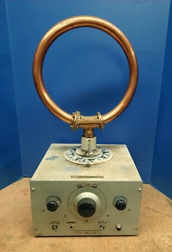 Front/top view of RMCA radio-direction-finding receiver with big loop on top, lagre calibrated tuning dial/knob, 2 smaller knobs and 2 toggle switches. 