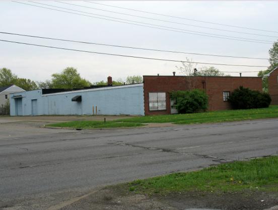 Photo of a medium size single story brick and cinder block building with 2 garage doors at the rear